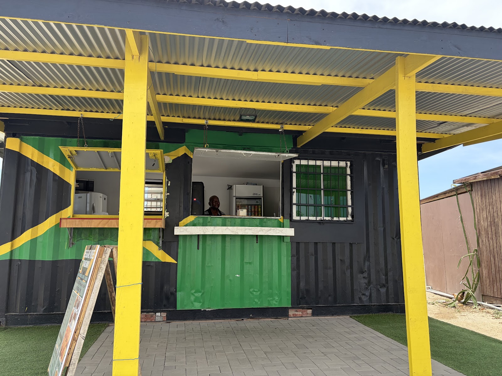 The Reggae Vibes Takeaway serving window — a shipping container painted as the Jamaican flag