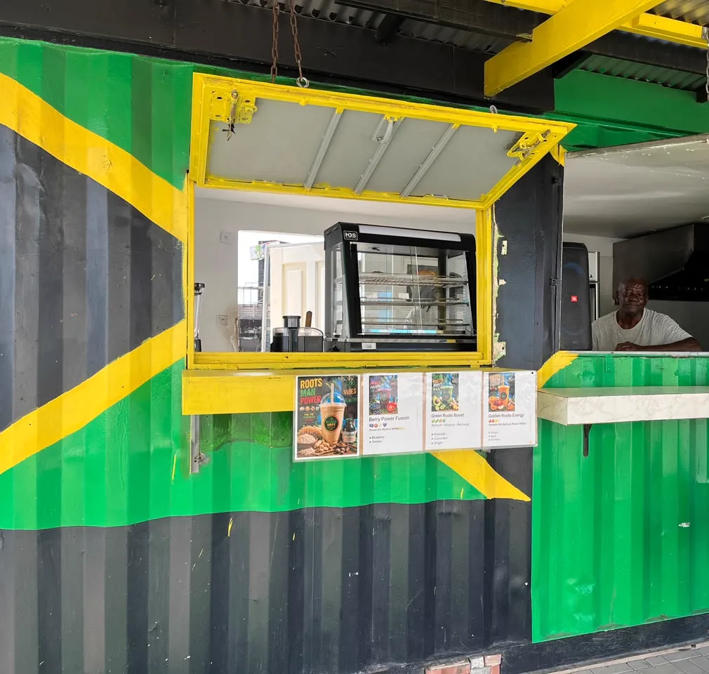 The Reggae Vibes Takeaway serving window — a shipping container painted as the Jamaican flag